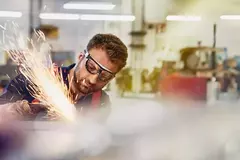 Male wearing safety glasses, grinding metal.